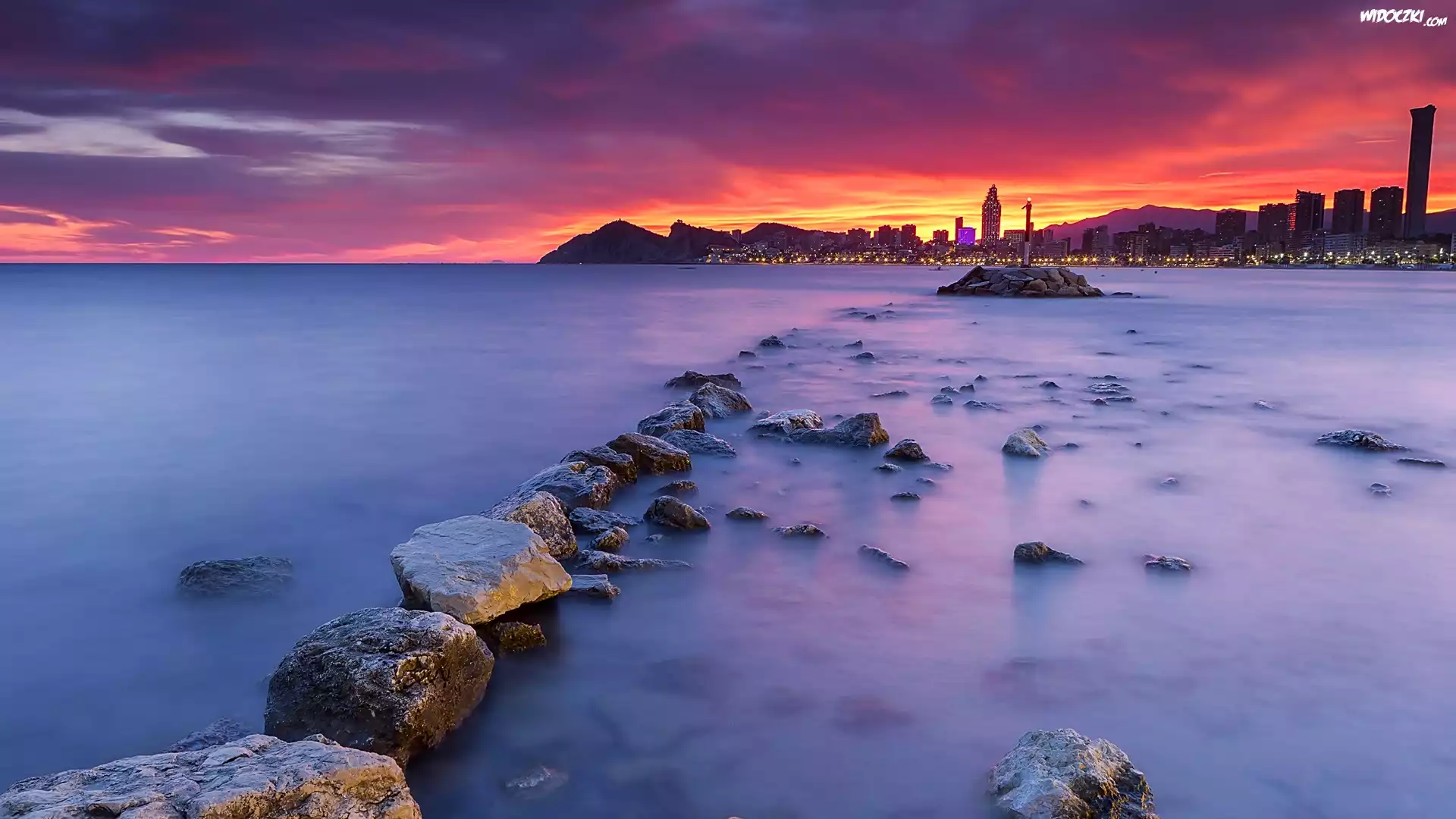 Hiszpania, Costa Blanca, Benidorm, Morze, Kamienie, Wieżowce, Światła, Chmury, Zachód słońca