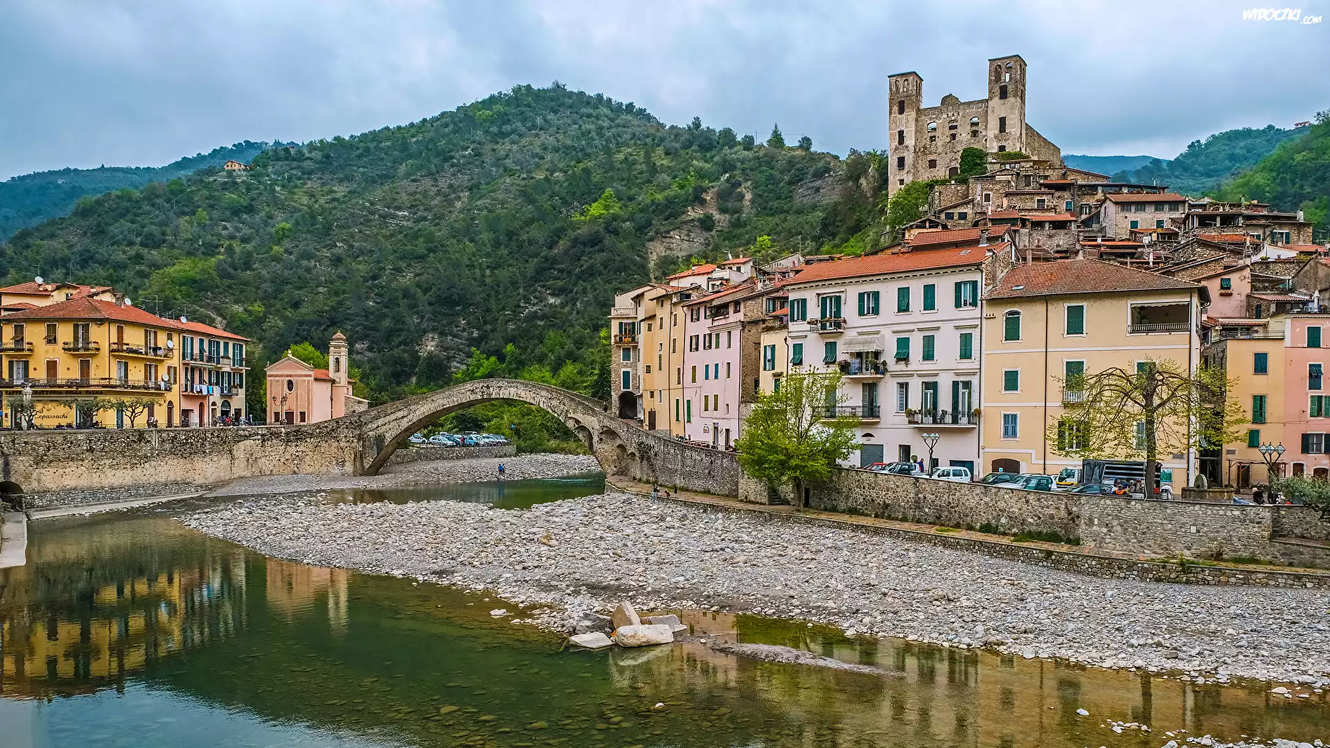 Włochy, Liguria, Miejscowość Dolceacqua, Domy, Rzeka Nervia, Kamienie, Most, Góry, Drzewa
