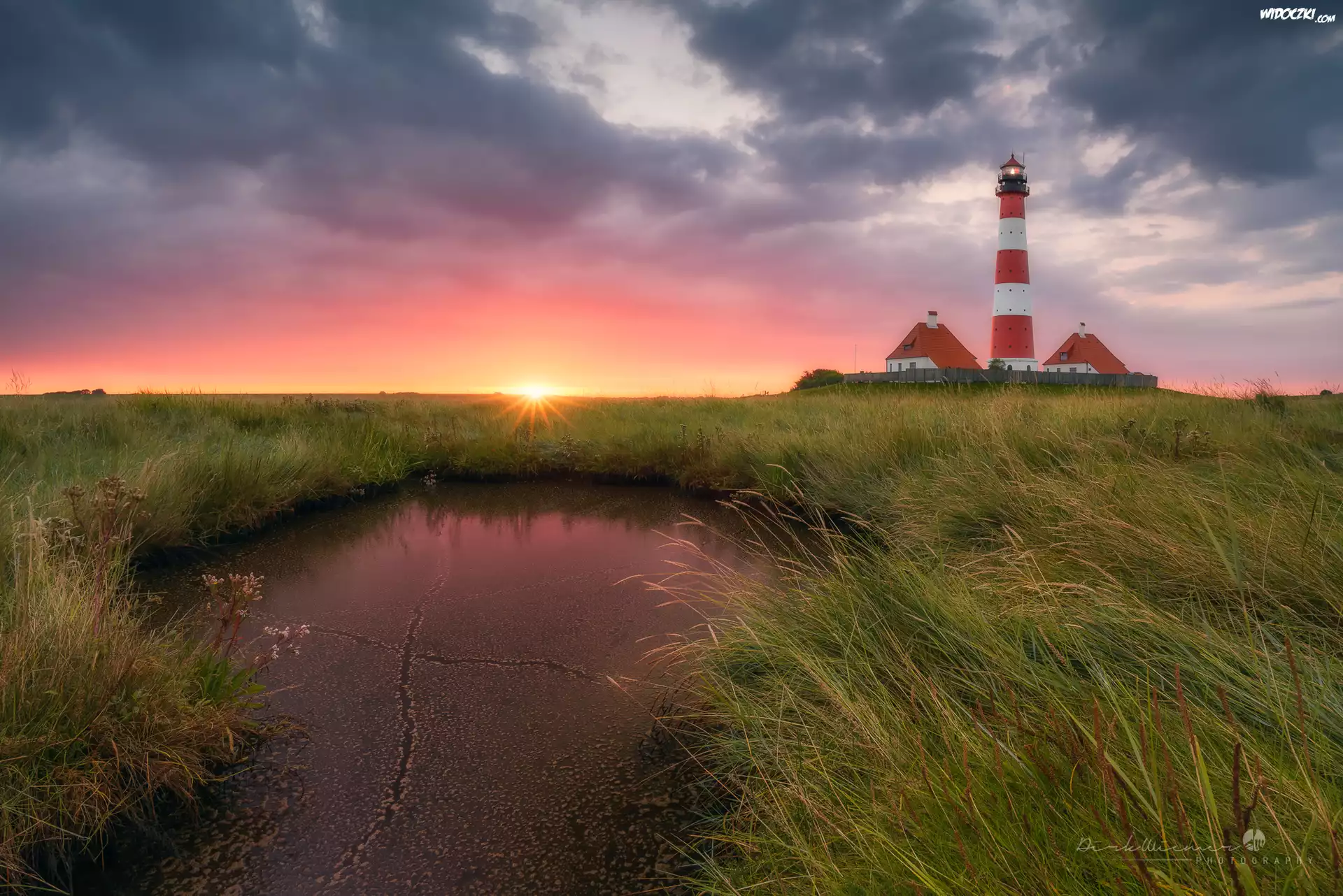 Latarnia morska Westerheversand, Kałuża, Trawy, Zachód słońca, Chmury, Nordfriesland, Niemcy