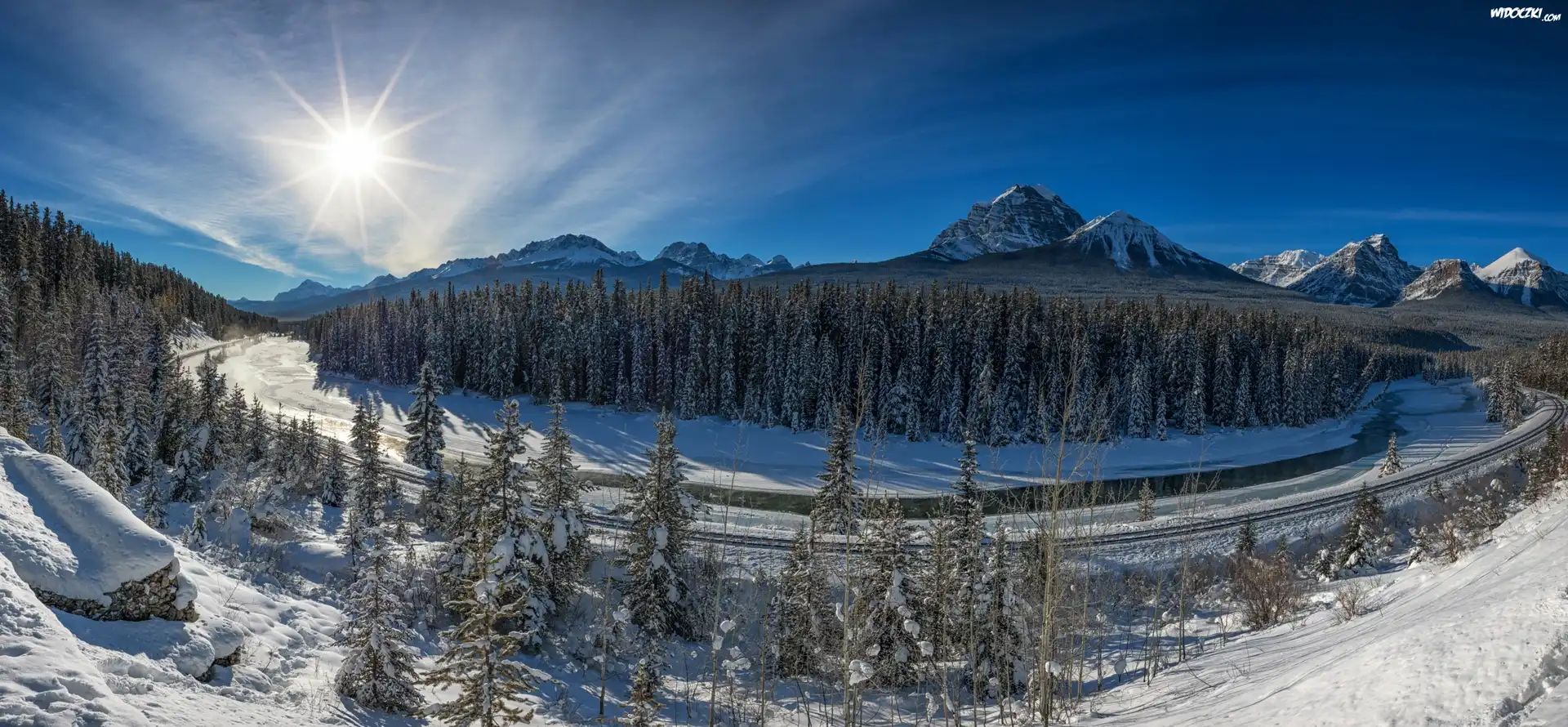 Kanada, Prowincja Alberta, Park Narodowy Banff, Dolina Bow Valley, Góry Skaliste, Drzewa, Rzeka Bow River, Tory kolejowe, Śnieg, Zima, Promienie słońca